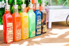 a row of colorful bottles sitting on top of a wooden table