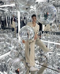 a woman standing in front of many shiny balls