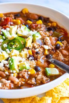 a white bowl filled with taco soup next to tortilla chips