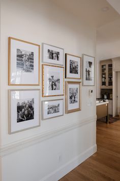 a wall with many pictures hanging on it's side and wood floors in the background