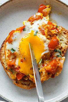 an egg is on top of bread in a white bowl with a knife and fork