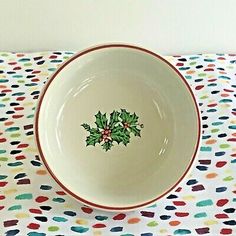 a white bowl with green holly on it sitting on a polka dot tablecloth covered table