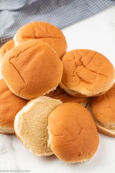 a pile of small hamburgers sitting on top of a white counter next to a blue towel