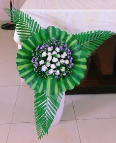 a bouquet of flowers is sitting on the floor next to a table with white linens