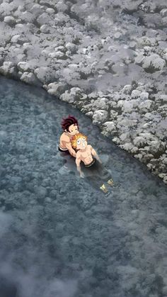 an aerial view of a man holding a baby in his arms while floating on the water