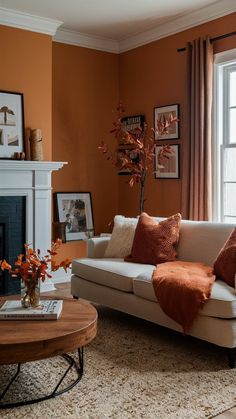 a living room with an orange wall and white couches in front of a fireplace