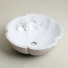 a white bowl with an ornate design on the bottom and sides, sitting on a table