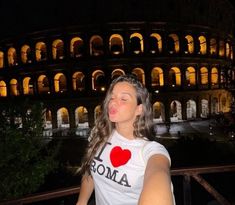 a woman standing in front of the colossion at night with her eyes closed