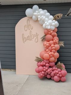 a balloon arch that says oh baby on it and balloons in the shape of flowers