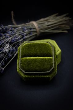 a small green box sitting on top of a table next to some dried lavenders