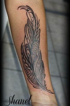 a black and white feather tattoo on the arm