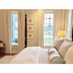 a large bed sitting in the middle of a bedroom next to two windows