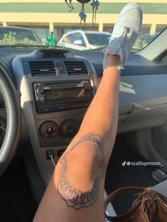 a woman's arm with a tattoo on it sitting in the driver's seat of a car