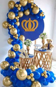 a blue and gold balloon arch with a crown on the top, surrounded by balloons