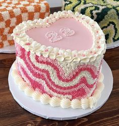 a pink and white cake sitting on top of a table next to two colorful pillows