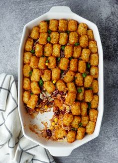 a casserole dish filled with tater tots and garnished with green onions