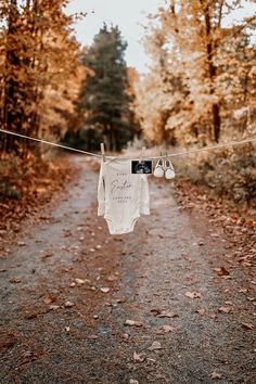 a baby's bodysuit hanging on a clothes line in the middle of a forest