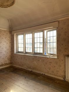 an empty room with wooden floors and wall paper on the walls is shown in this image