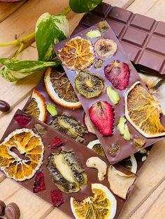 chocolate bar with fruit and nuts on it next to some leaves, berries, and other fruits