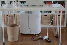 a laptop computer sitting on top of a white desk next to a wicker basket