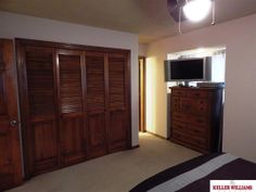 a bedroom with wooden closet doors and a flat screen tv