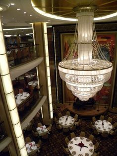 a chandelier hanging from the ceiling in a dining room on a cruise ship