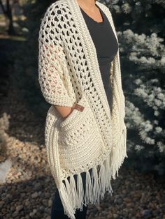 a woman wearing a white crocheted shawl with fringes on the sides