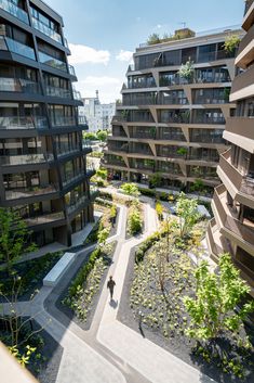 an aerial view of two buildings with trees in the foreground and people walking on the other side