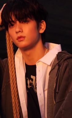 a young man wearing a white shirt and black tie holding a rope in front of his head