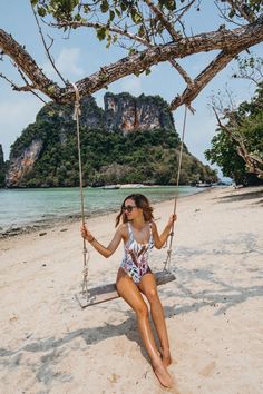 a woman sitting on a swing at the beach