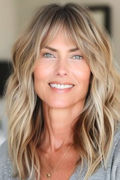 Mid-Length Waves With Bangs Haircut on smiling woman with blonde hair. Women's Haircut With Bangs, Layered Hair With Side Bangs Mid Length, Medium Length Hair Styles Layers, Fine Blonde Hair With Bangs, Medium Hair Layers With Bangs, Chandelier Layers Haircut, Side Swept Bangs Medium Hair With Layers, Blonde Balayage With Bangs, Medium Length Layered Hair With Bangs