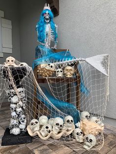 a skeleton sitting on top of a chair next to a net with skulls in it