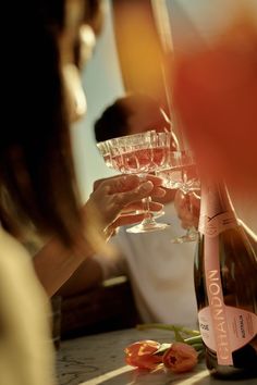 two people are toasting with wine glasses in front of them and flowers on the table