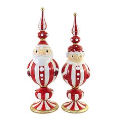 two red and white santa claus ornaments sitting on top of each other in front of a white background