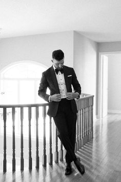 a man in a tuxedo is standing on a stair case and looking down