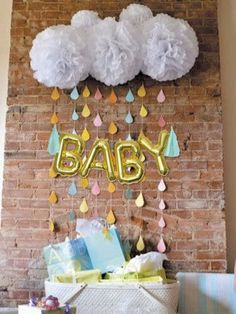 a baby shower party with balloons and streamers hanging from the brick wall above it