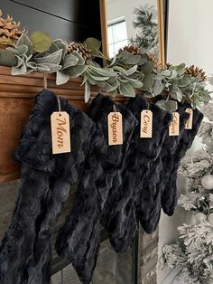 christmas stockings hanging from a mantel decorated with greenery