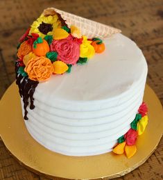 a white cake decorated with flowers and icing on a gold plated platter