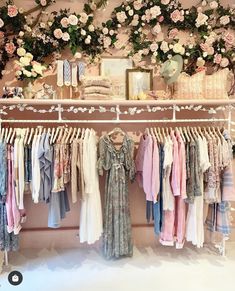 a clothing rack with clothes and flowers on the wall