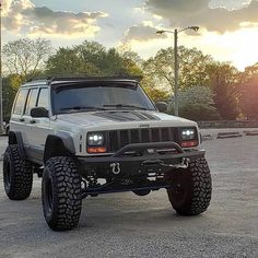 a white jeep parked in a parking lot with the sun shining down on it's headlamps