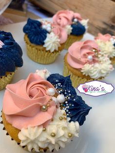 cupcakes decorated with pink, blue and white frosting on top of a plate