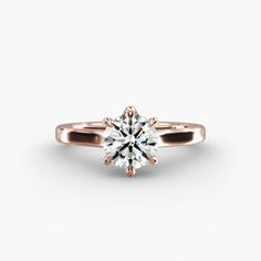 a rose gold engagement ring with a round brilliant diamond in the center, on a white background