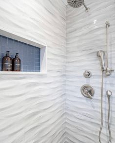 a shower with blue and white tile on the wall next to it is shown in this bathroom