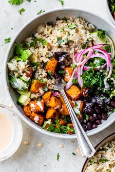 a bowl filled with rice, beans and vegetables next to two bowls full of salad