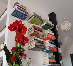 a vase filled with red flowers sitting on top of a table next to a bookshelf