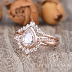 a close up of a ring on a table with rose petals in the background and two peaches behind it