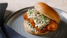 a chicken sandwich is sitting on a plate with a blue cloth next to it and a napkin