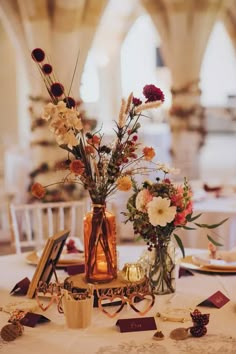 two vases filled with flowers sitting on top of a white tablecloth covered table