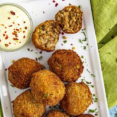 some fried food is on a white plate next to a small bowl of ranch dressing