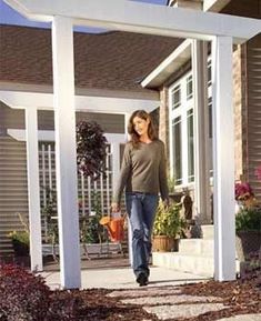 a woman walking down a sidewalk in front of a house